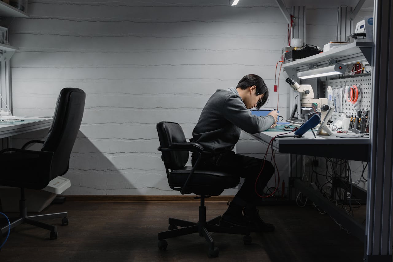 Focused engineer working on electronics repair in a tech workshop setting.